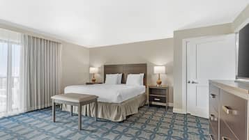 A hotel room with a bed, bedside tables, a bench, a TV, and a wardrobe.