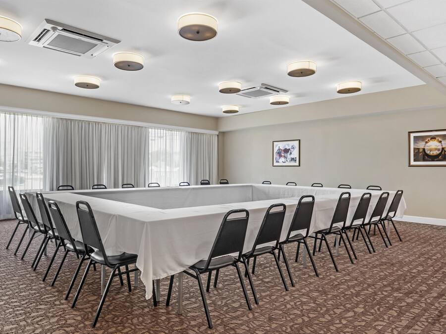 Un salón de conferencias con una larga mesa, sillas, luces en el techo y una alfombra estampada.