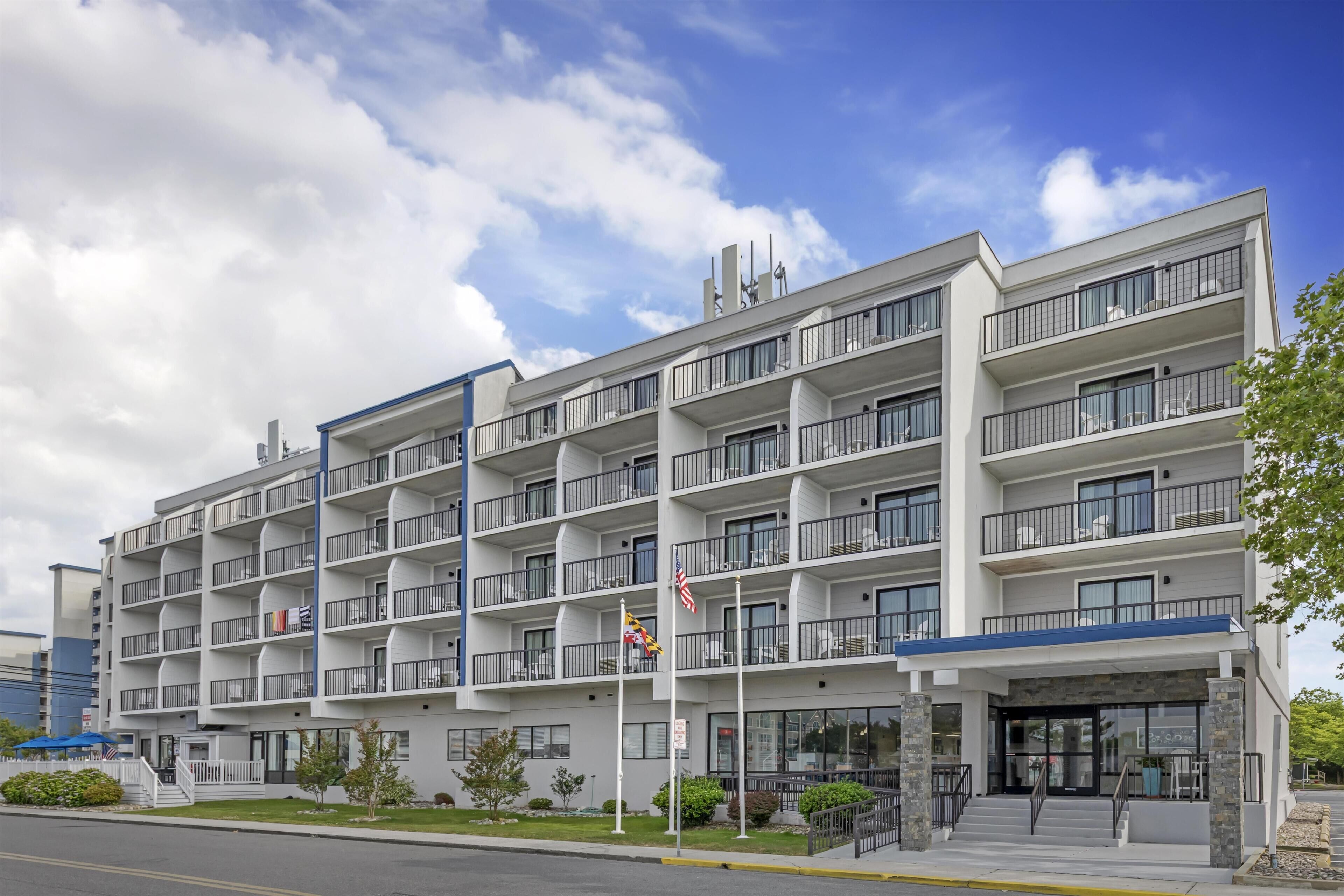 A multi-story hotel with balconies, a flag, and a clear sky.