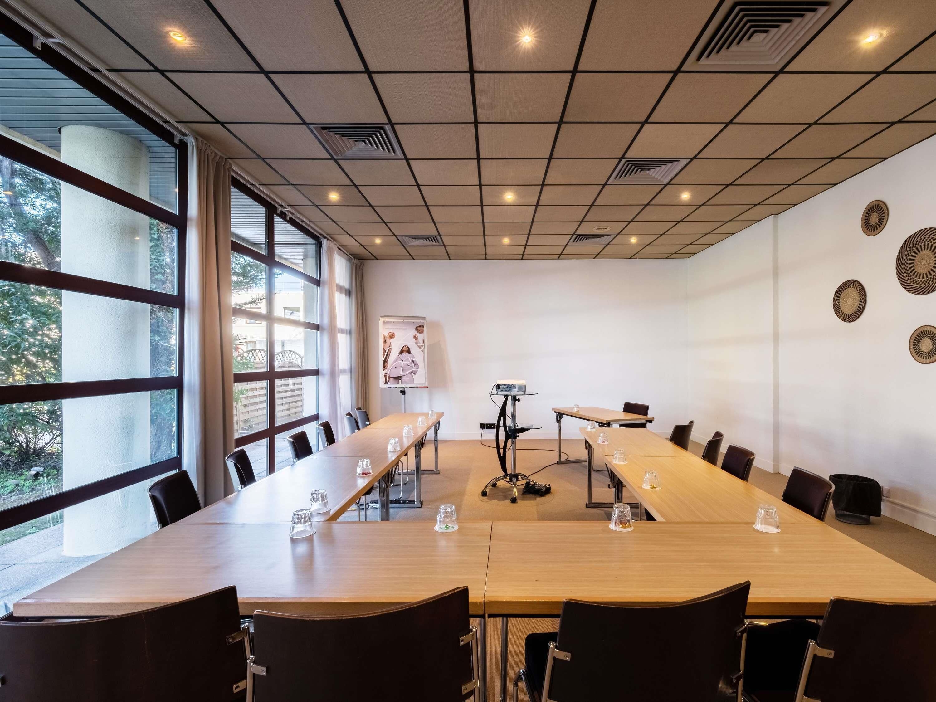 A conference room with a long table, chairs, a projector, and a poster on the wall.