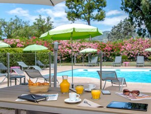 Una piscina al aire libre de temporada, sombrillas