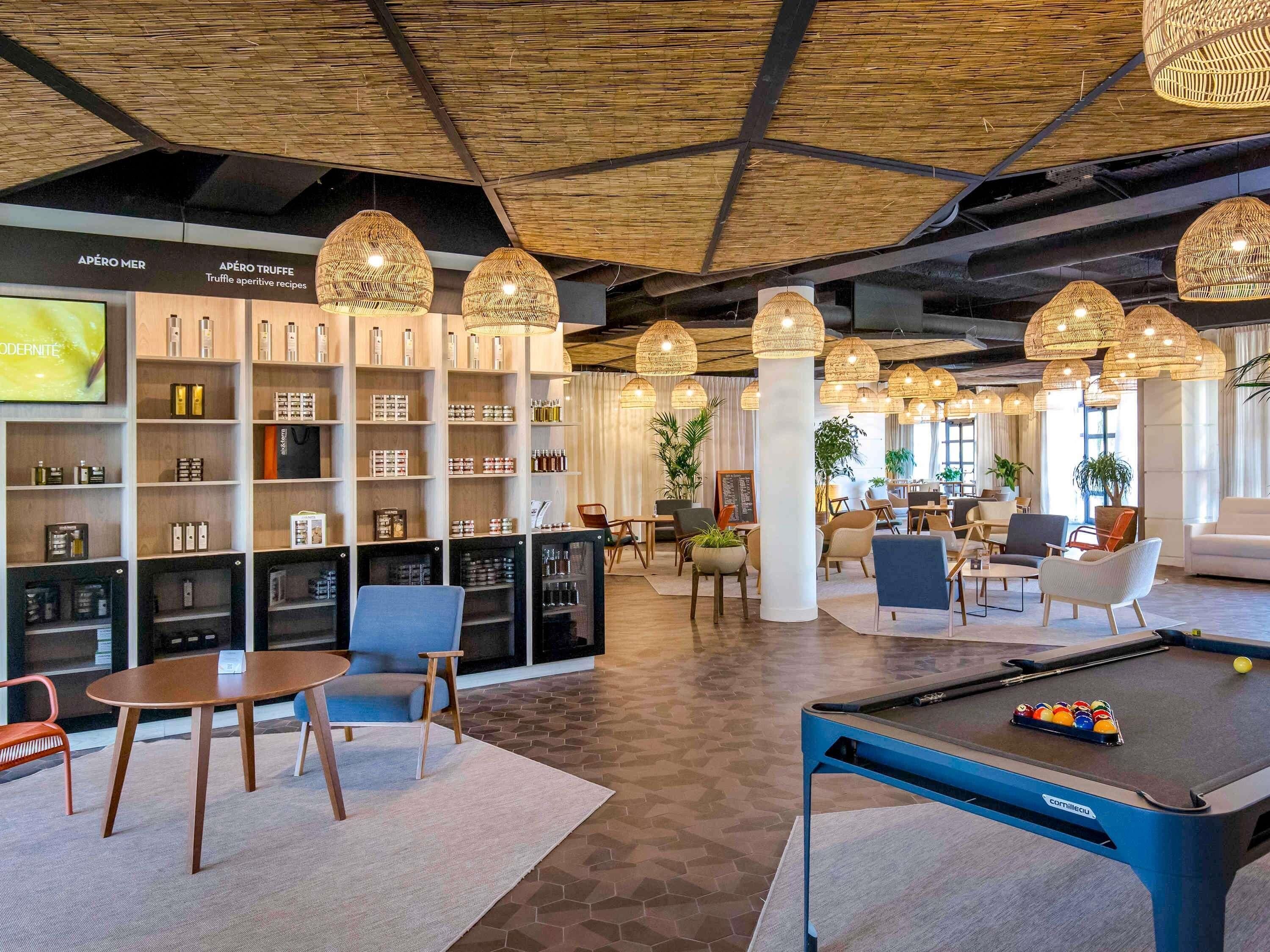 A modern lounge area with a pool table, seating, and a bar area with shelves of products.