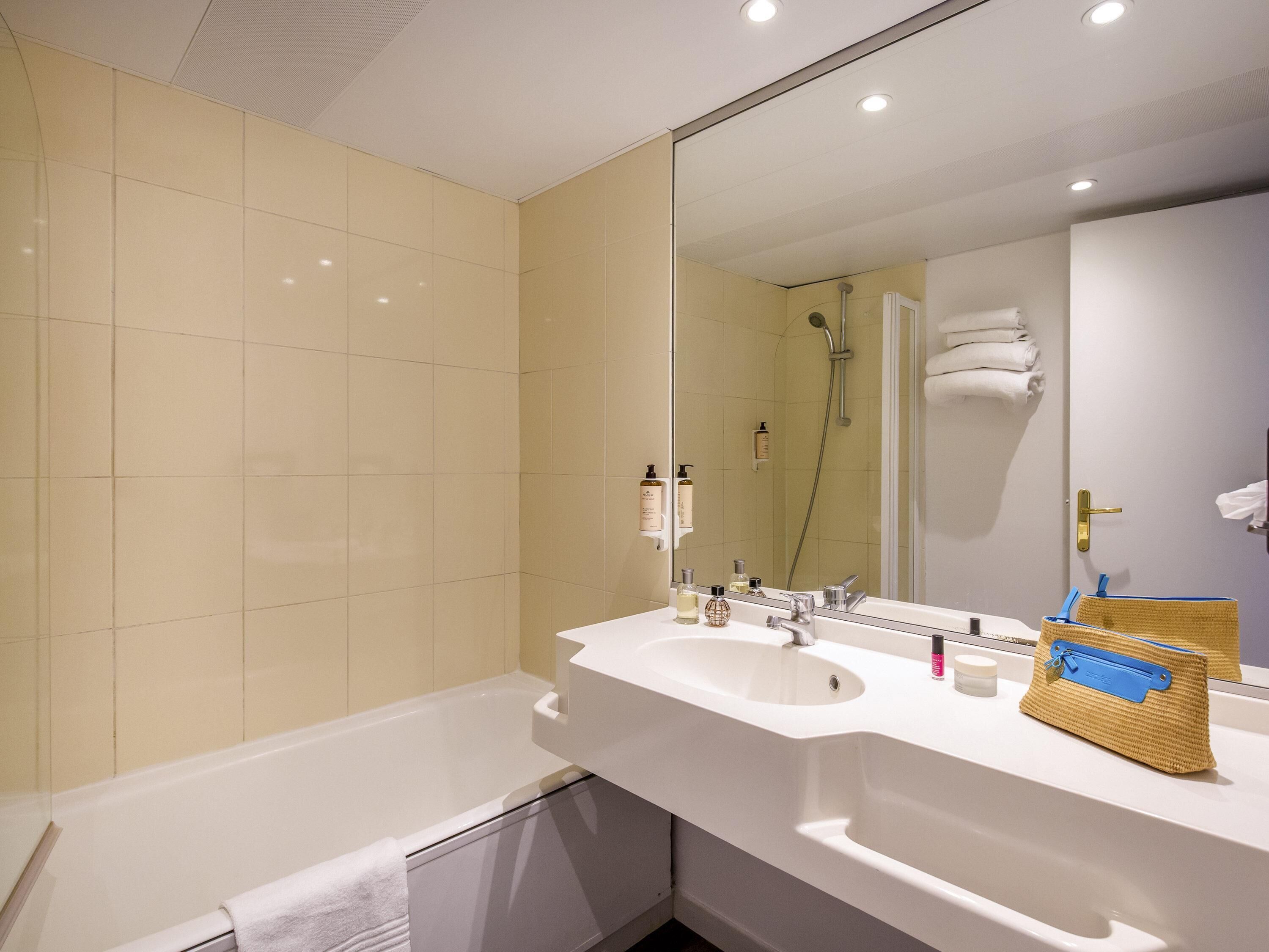 A modern bathroom with a bathtub, a large mirror, and a sink.