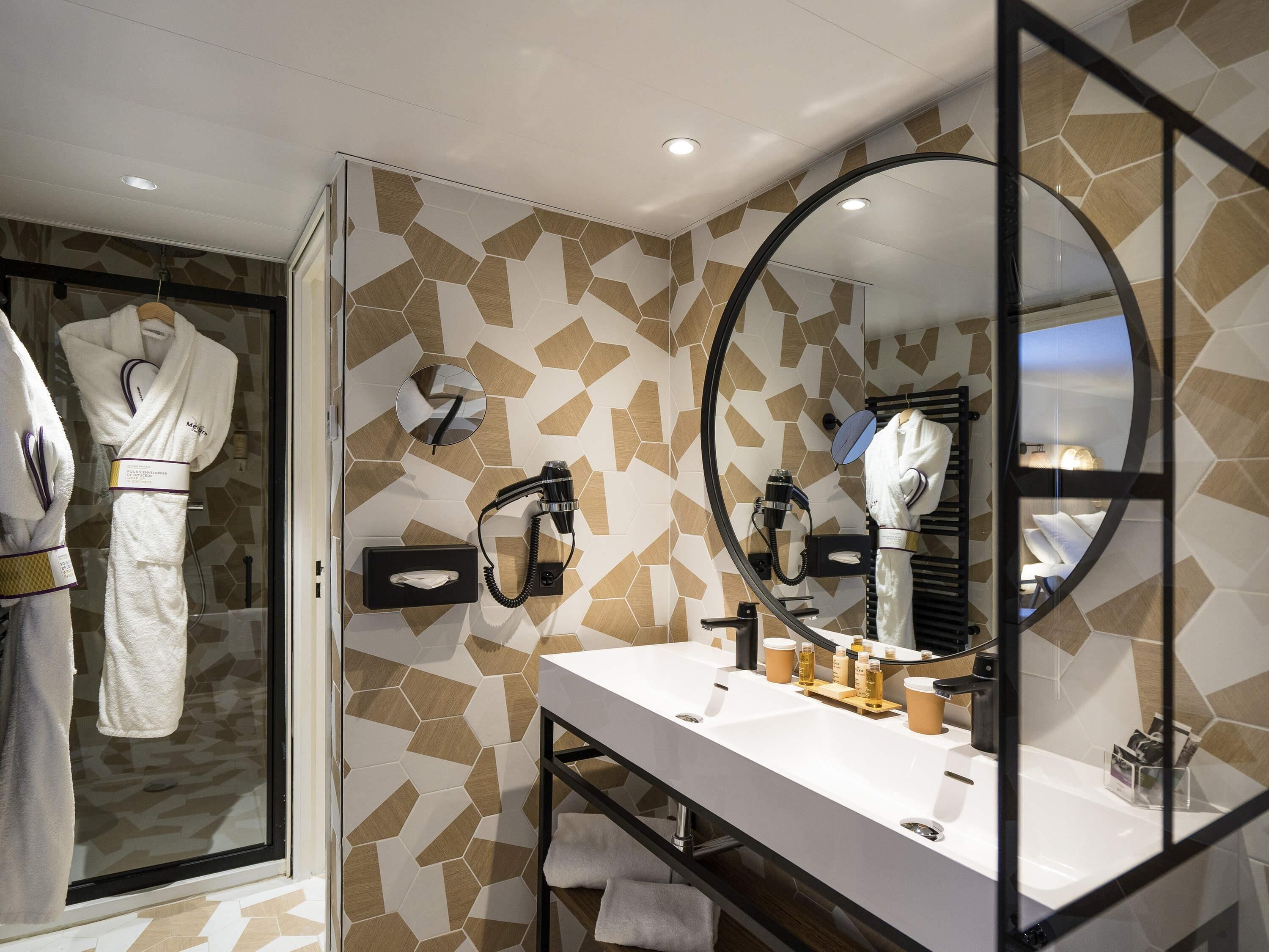 Un baño moderno con un espejo grande, un tocador con lavamanos y una cabina de ducha de vidrio.