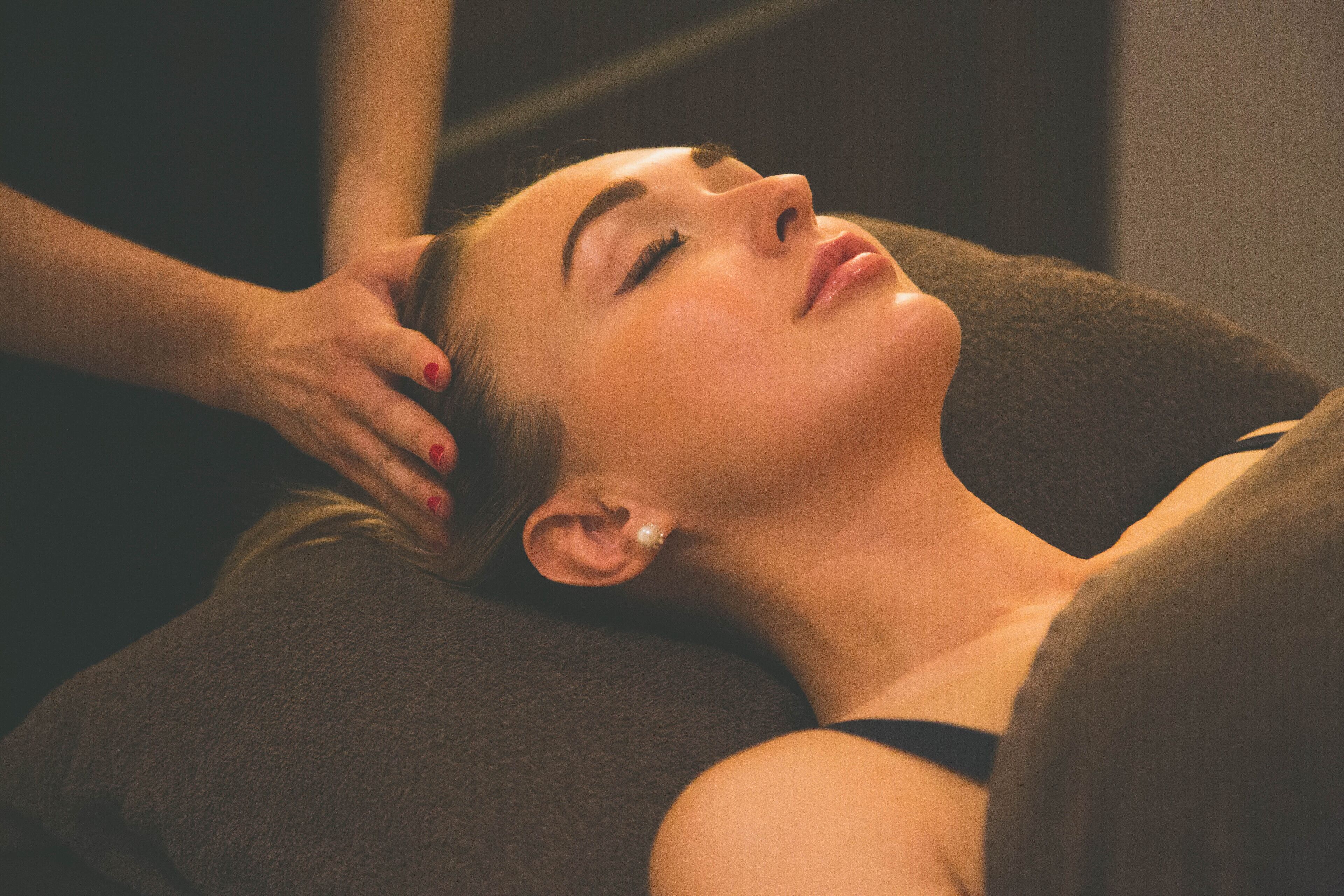 Une personne allongée sur une table de massage, la main d’un thérapeute posée sur sa tête.