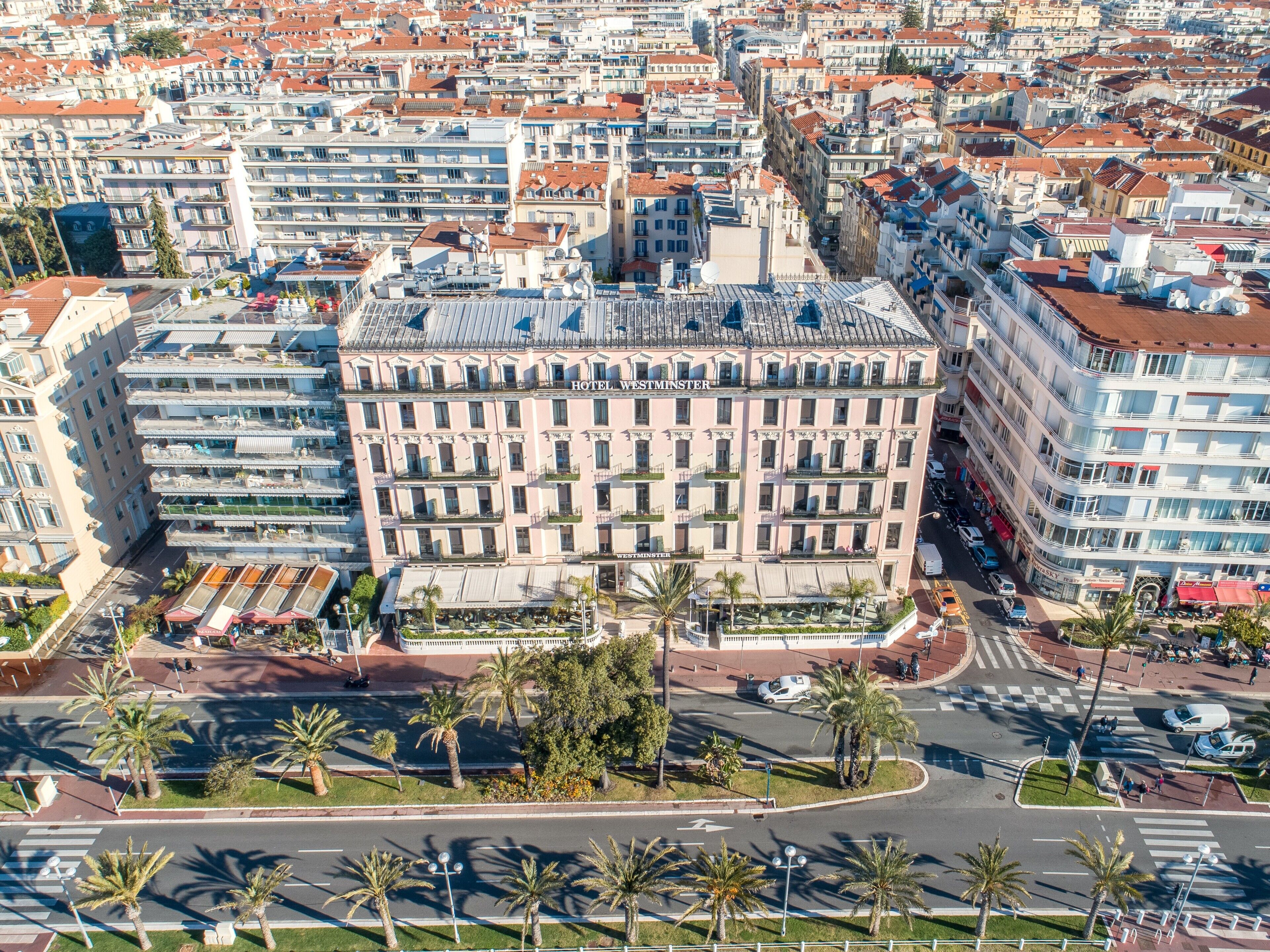 A multi-story hotel with a central courtyard, surrounded by other buildings.