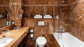 Une salle de bain avec des murs en marbre, une baignoire, des toilettes et un lavabo.