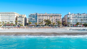 A beachfront hotel with multiple floors, palm trees, and a clear blue sky.
