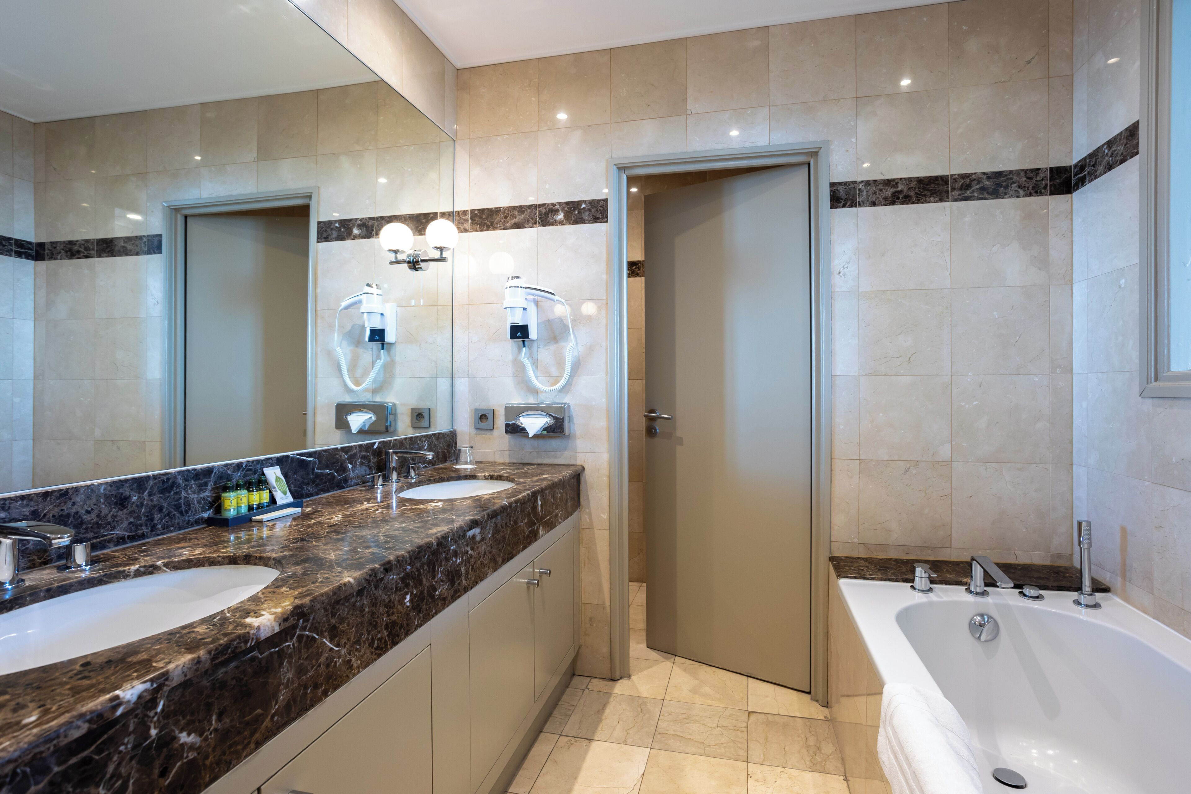 A modern bathroom with two sinks, a bathtub, and a shower.