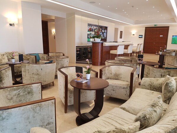 Un hall de hotel con zonas de estar, un mostrador de recepción y un bar.
