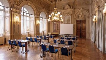 Un vaste hall doté d’un plafond richement décoré, de lustres et d’un tableau blanc à l’avant.