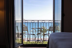 A balcony with a view of the sea, two chairs, a table, and a railing. - Westminster Hotel & Spa Nice (Nice)