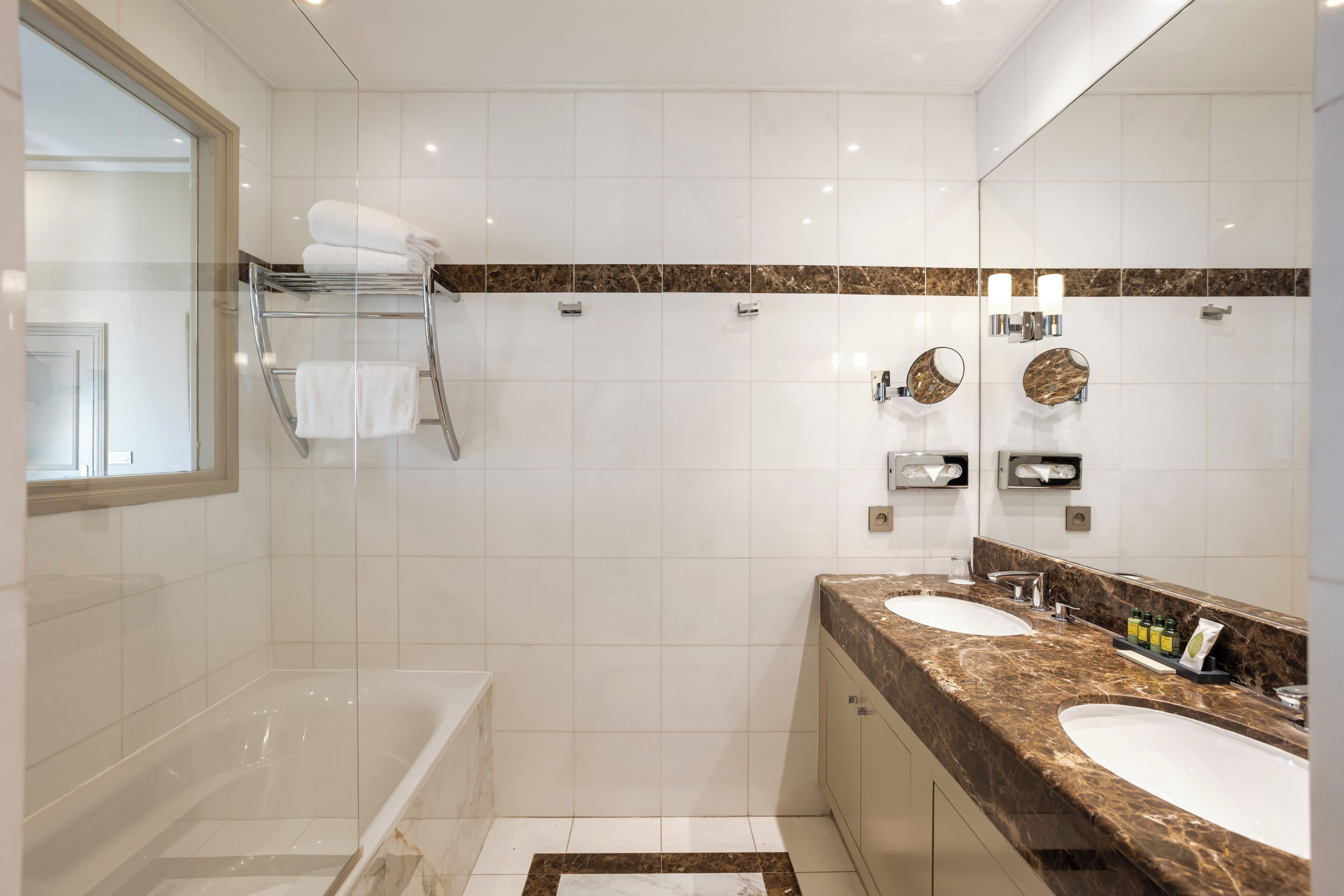 Un baño moderno con una bañera, dos lavamanos, una cabina de ducha de vidrio y encimera de mármol.