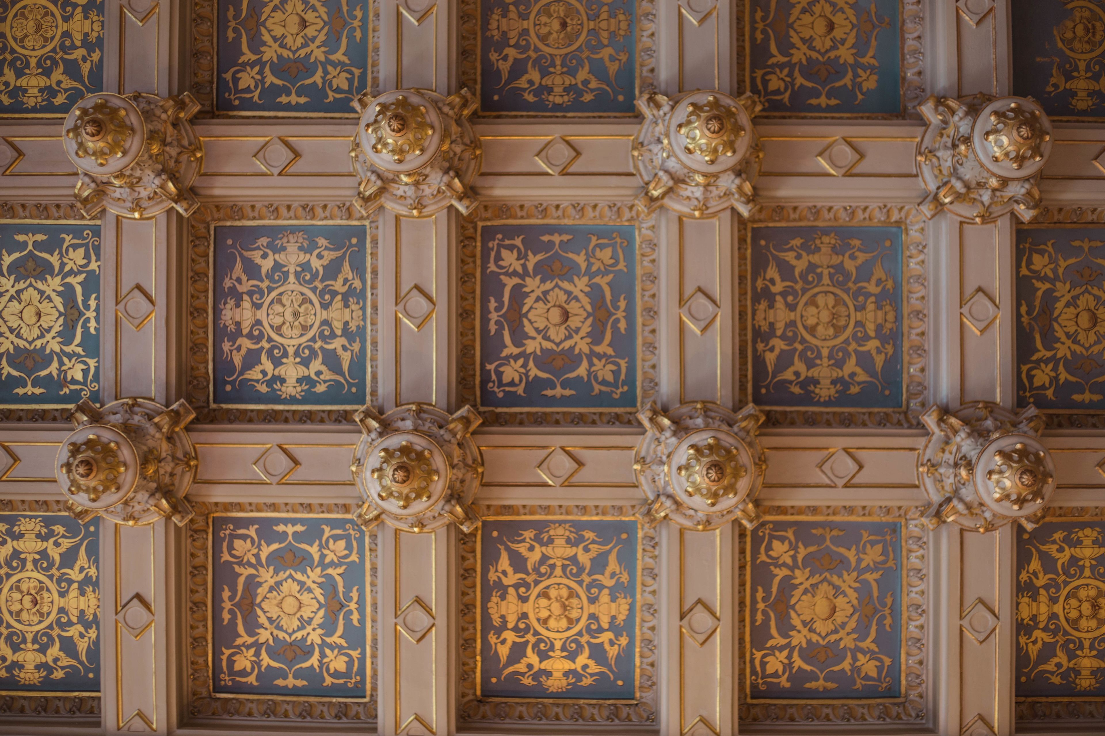 A ceiling with ornate gold and blue patterns and decorative medallions.