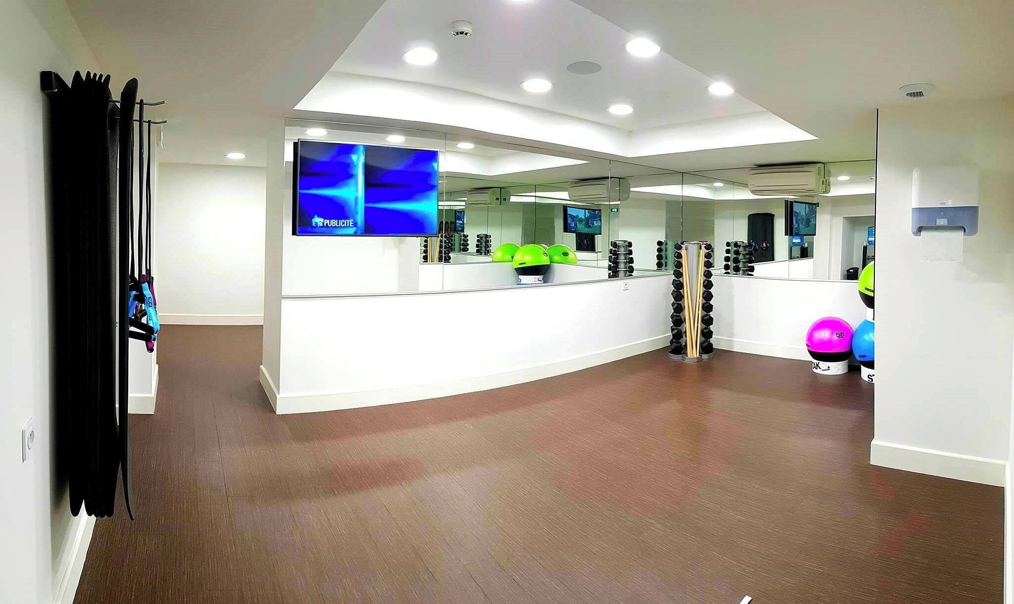 Un espace d’accueil moderne avec un comptoir blanc incurvé, un téléviseur à écran plat et un grand miroir.