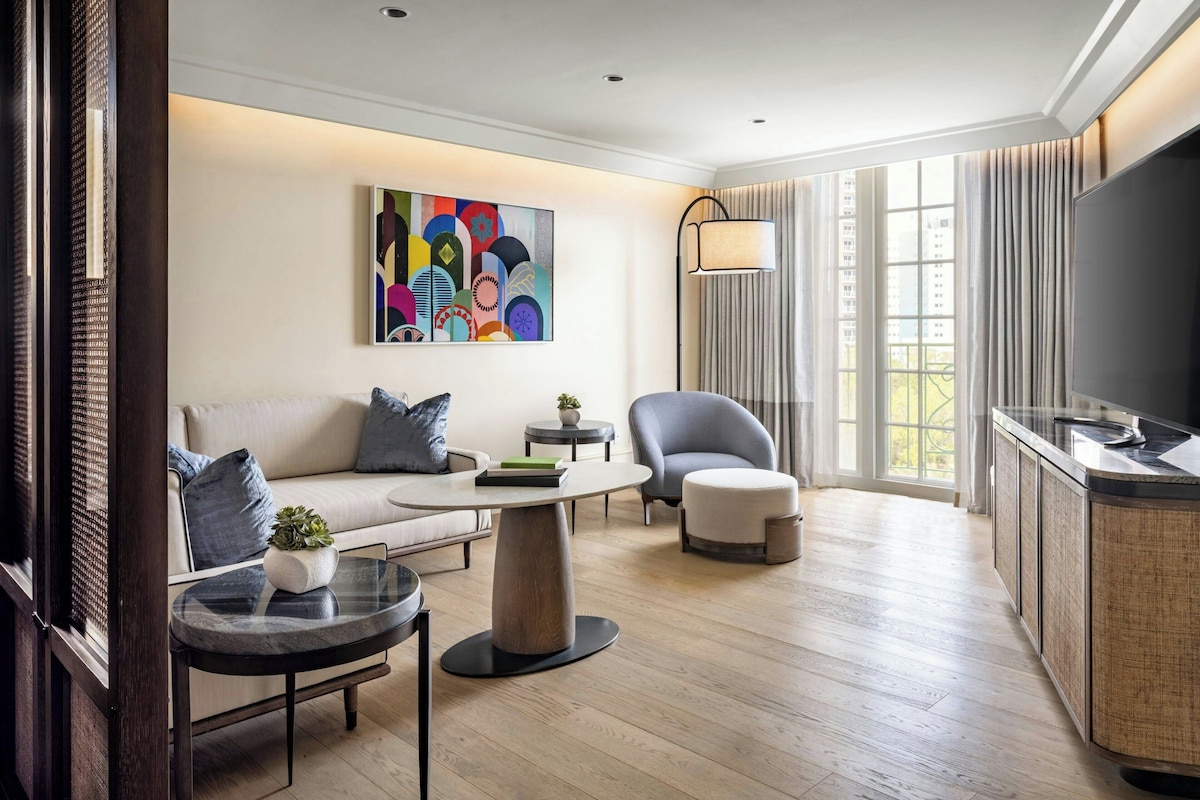 Un salon moderne avec un canapé, un fauteuil, une table ronde et un tableau accroché au mur.