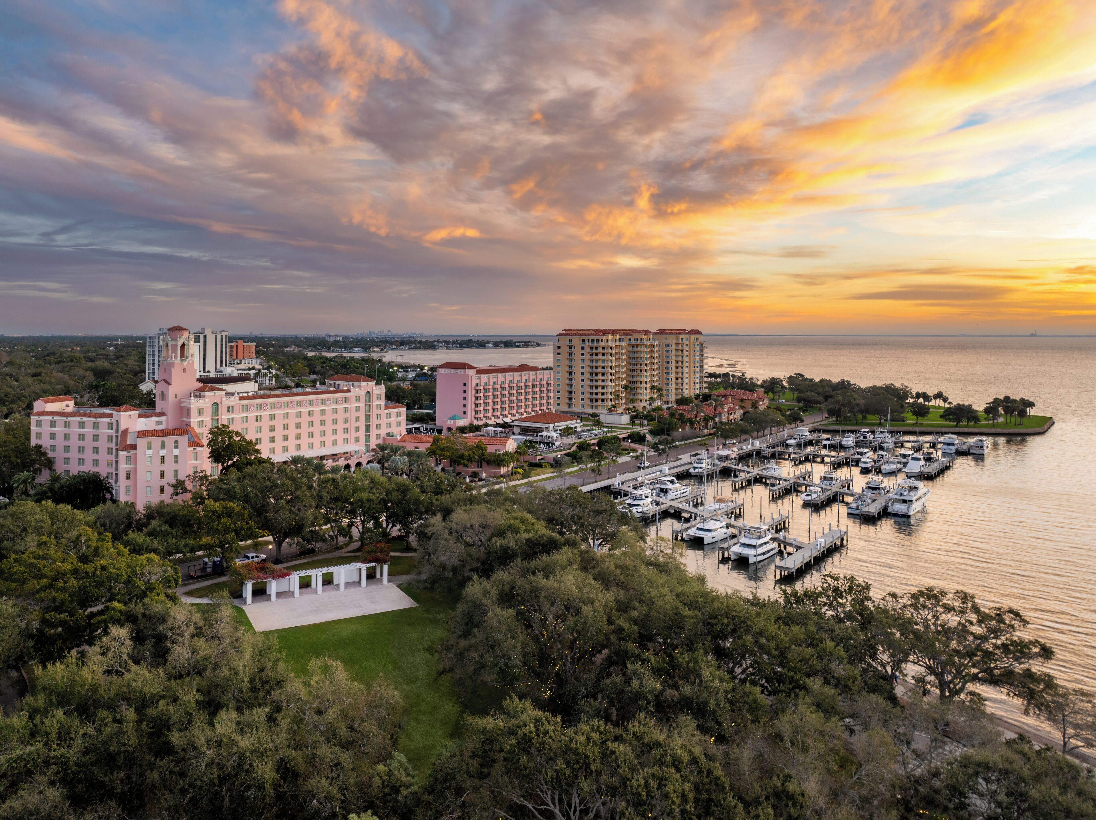 Um hotel à beira-mar com vários edifícios, uma marina e vista para o pôr do sol.