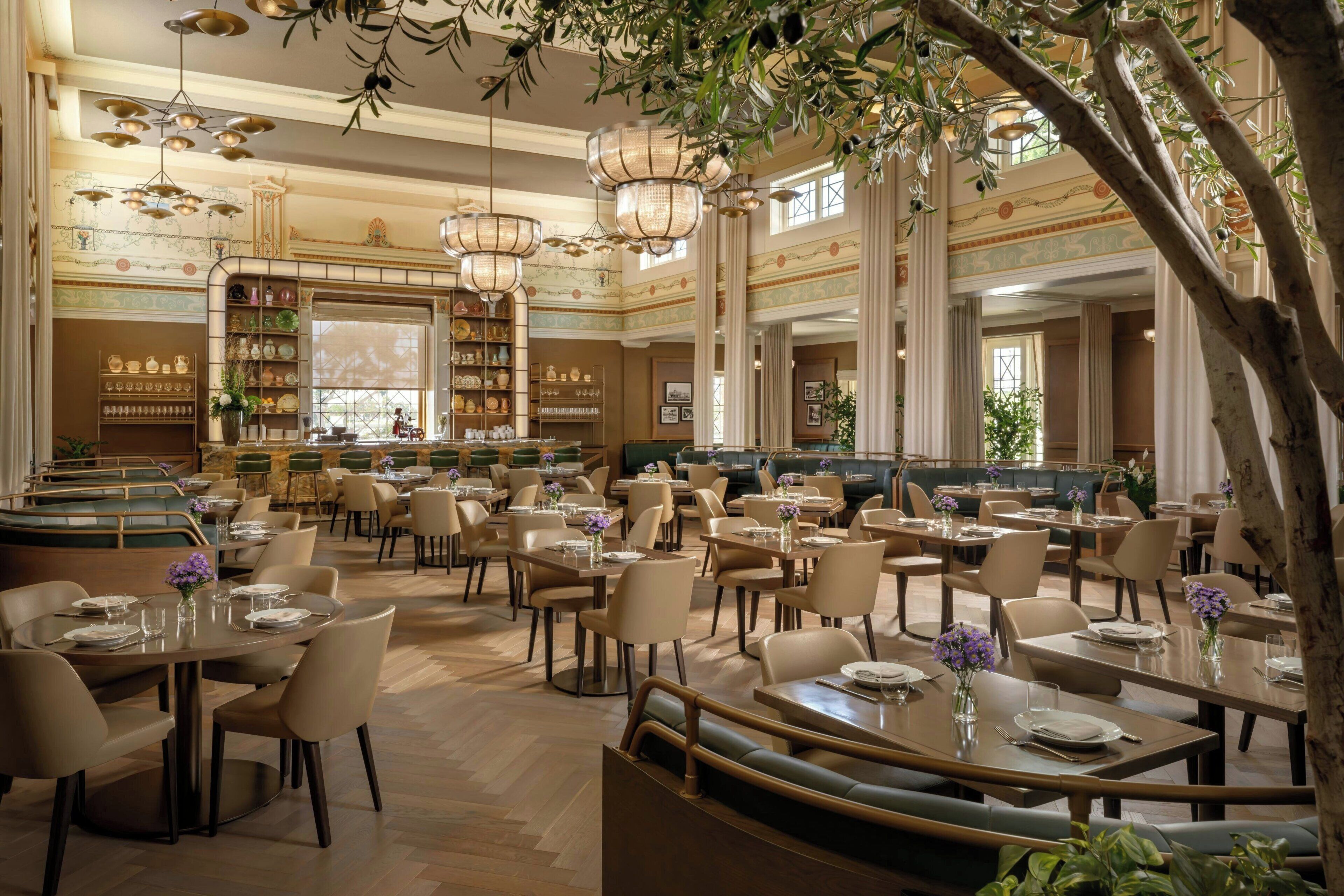 A spacious restaurant with multiple dining areas, high ceilings, and decorative lighting fixtures.