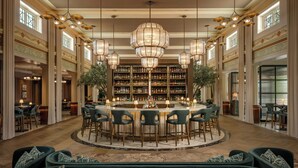 Eine großzügige Bar mit einer zentralen Bar, verschiedenen Sitzgelegenheiten und einer großen Chandelier.