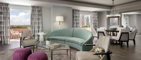 A modern living room with a teal sofa, purple ottomans, and a glass coffee table.