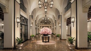 A grand hallway with a chandelier, potted plants, and a floral centerpiece. - The Vinoy Resort & Golf Club, Autograph Collection (St. Petersburg)