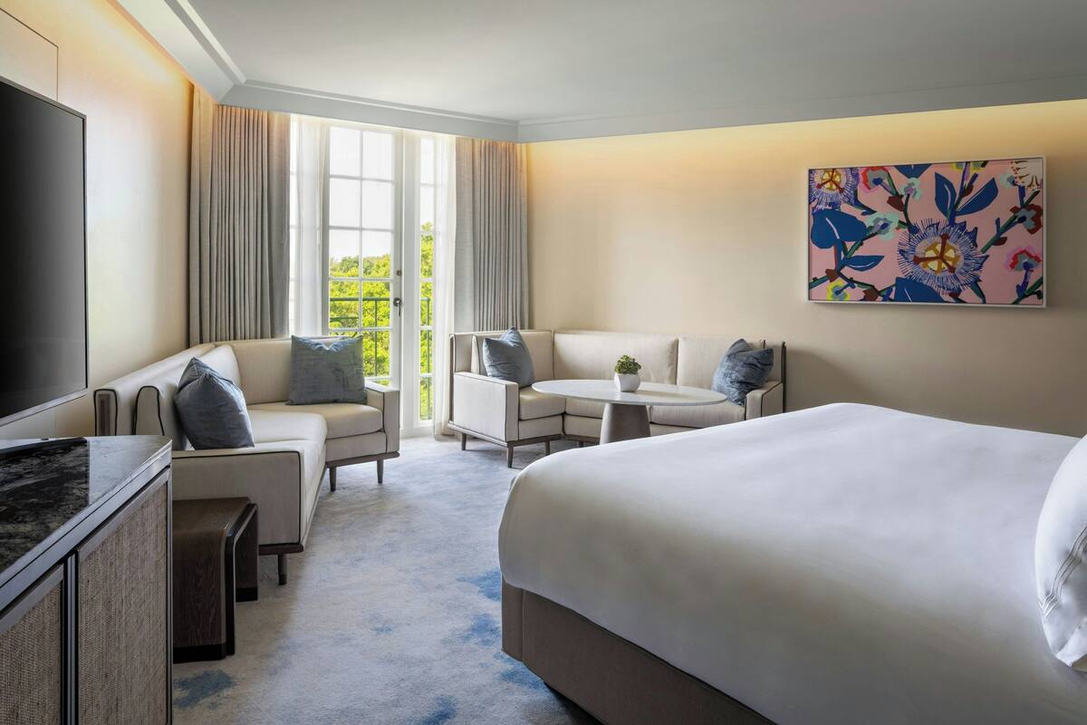 Ein Hotelzimmer mit einem großen Bett, einer Couch, einem kleinen Tisch und einem Fernseher.
