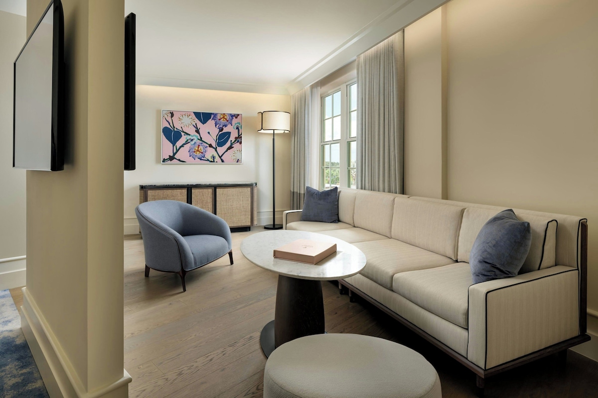Un salon moderne avec un canapé beige, une table basse ronde et un fauteuil bleu.