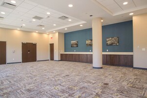 A spacious room with a patterned carpet, wooden cabinets, and a blue accent wall.