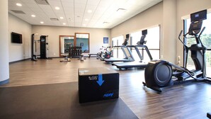 Un gimnasio con equipamiento de ejercicio, un espejo grande y vistas al exterior.