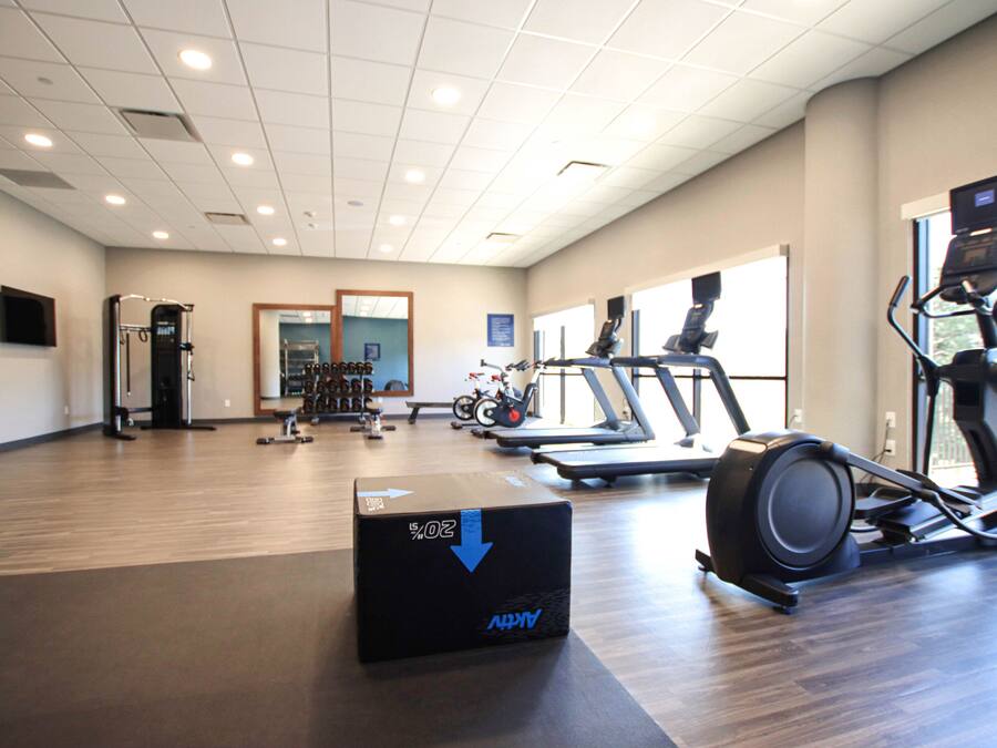 Un gimnasio con equipamiento de ejercicio, un espejo grande y vistas al exterior.