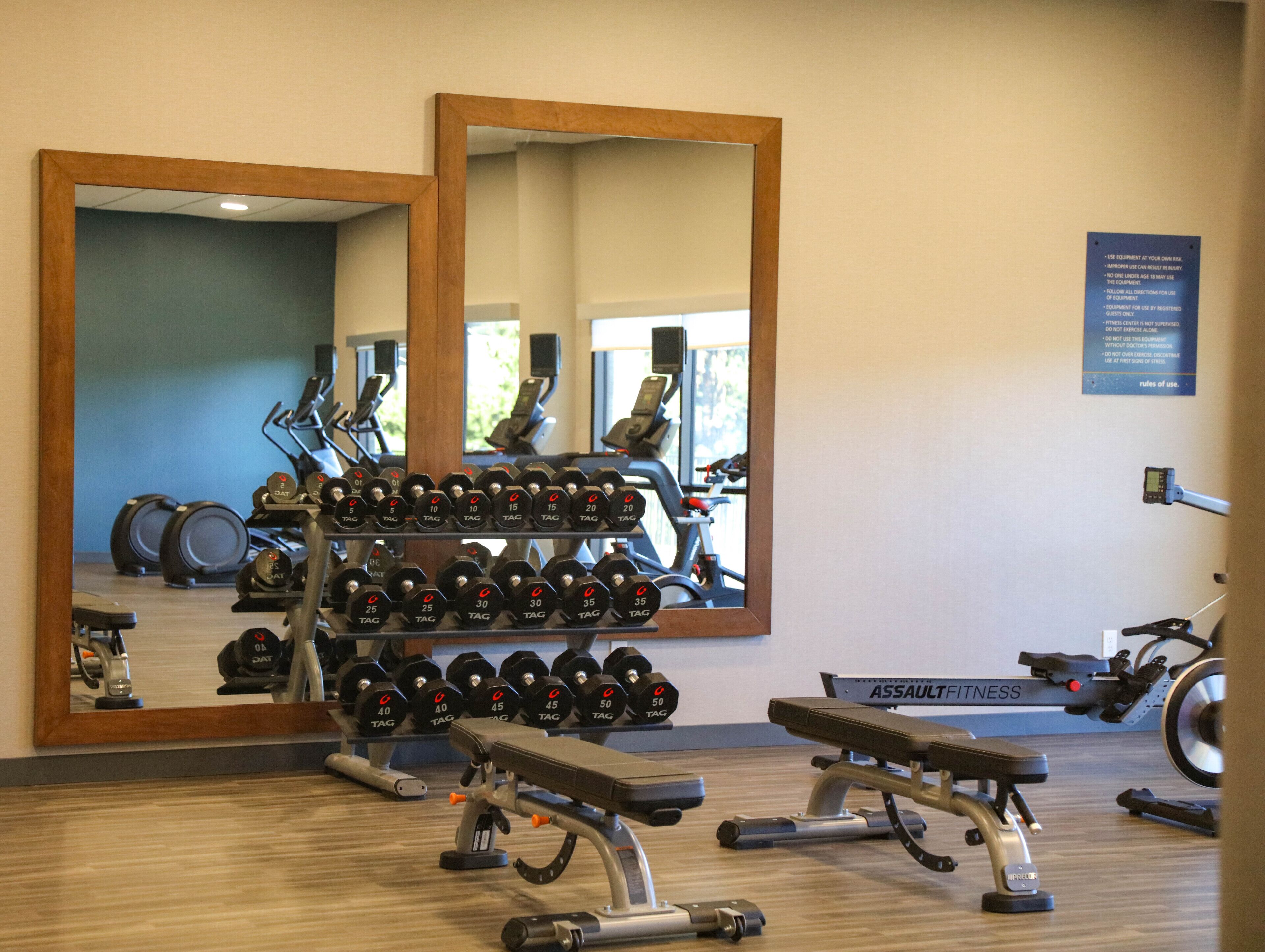 A gym with weightlifting equipment, exercise machines, and mirrors.