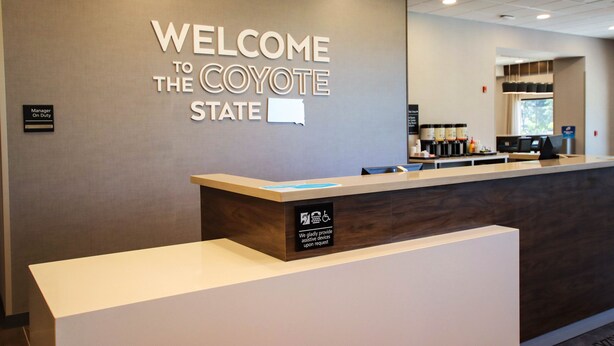 Un mostrador de recepción con un letrero que dice "WELCOME TO THE CAYOTE STATE" y un letrero que indica "Manager On Duty".