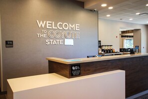 Un mostrador de recepción con un letrero que dice "WELCOME TO THE CAYOTE STATE" y un letrero que indica "Manager On Duty".