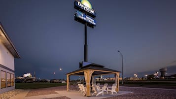 A Days Inn sign, outdoor seating area with chairs, and a covered pavilion.