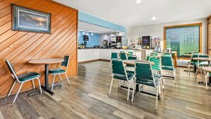 A modern restaurant with wooden paneling, green chairs, and a kitchen area in the background. - Days Inn by Wyndham Mitchell SD (Mitchell)