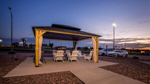 A covered outdoor seating area with chairs and a table, surrounded by a gravel area and a paved walkway. - Days Inn by Wyndham Mitchell SD (Mitchell)