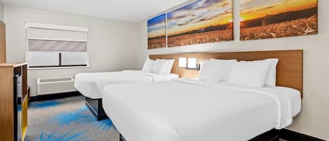 Une chambre d’hôtel avec deux lits, une grande fenêtre et une vue sur le coucher du soleil.