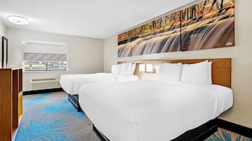 A hotel room with a large bed, a window with a view, and a painting of a waterfall.