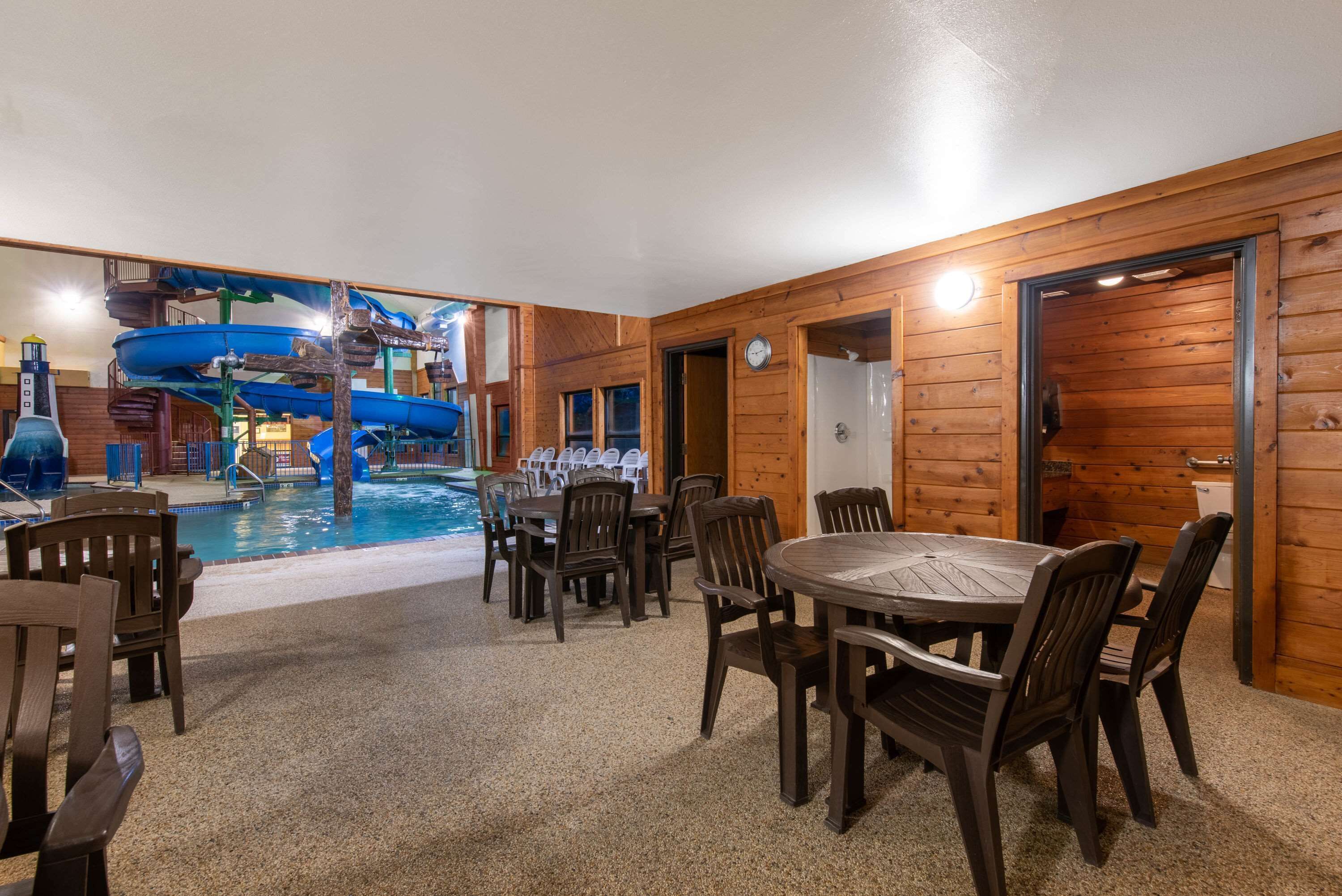 A wooden interior with a pool area, including a table and chairs, and a water slide.