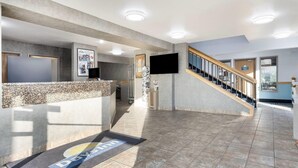 A hotel reception area with a reception desk, a staircase, and a wall-mounted TV. - Days Inn by Wyndham Mitchell SD (Mitchell)