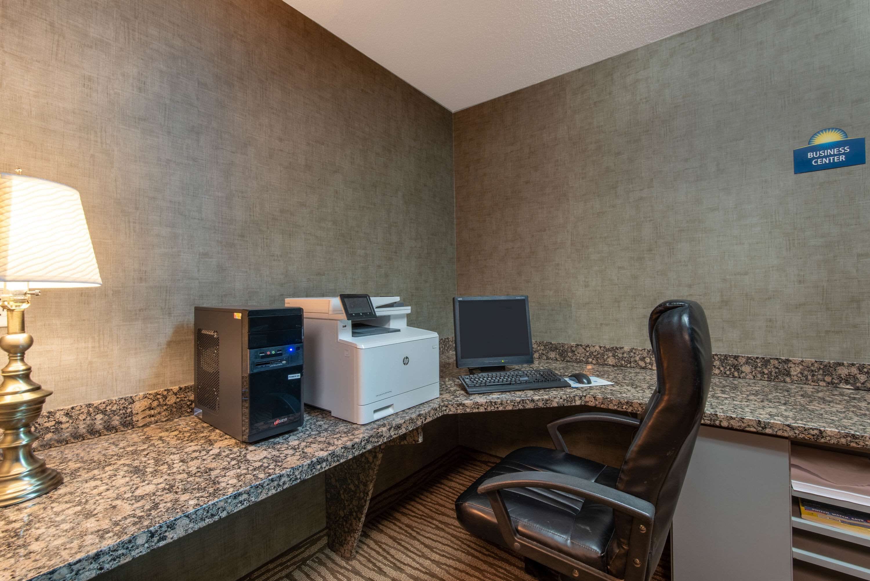 A business center with a desktop computer, printer, and chair.