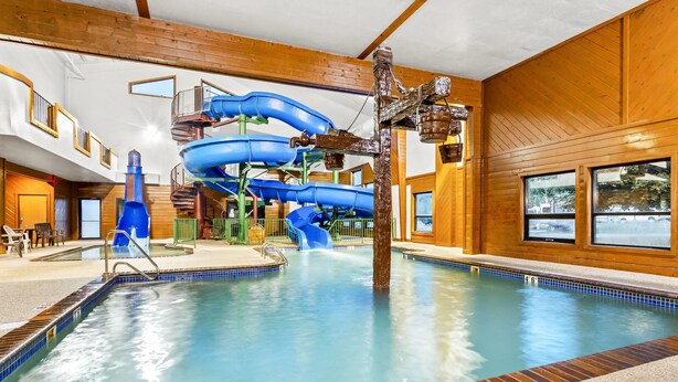 An indoor swimming pool with a water slide, wooden walls, and a clear view of the pool area. - Days Inn by Wyndham Mitchell SD (Mitchell)