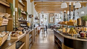 A spacious cafe with wooden beams, a central seating area, and a variety of baked goods and beverages on display. - Best Western Plus Hotel Hebron (Copenhagen)