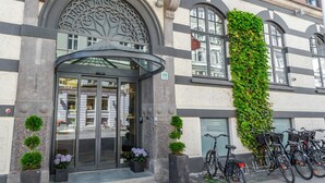 A hotel entrance with a glass door, a decorative metal arch, and a green ivy-covered wall. - Best Western Plus Hotel Hebron (Copenhagen)