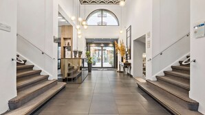 A hotel lobby with a central staircase, a reception desk, and a view through the glass doors. - Best Western Plus Hotel Hebron (Copenhagen)