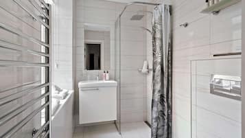A modern bathroom with a glass shower enclosure, a white sink with toiletries, and a mirror above the sink.