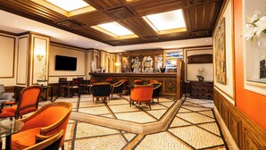 A bar area with a tiled floor, wooden ceiling, and orange chairs. - SANA Rex Hotel (Lisbon)