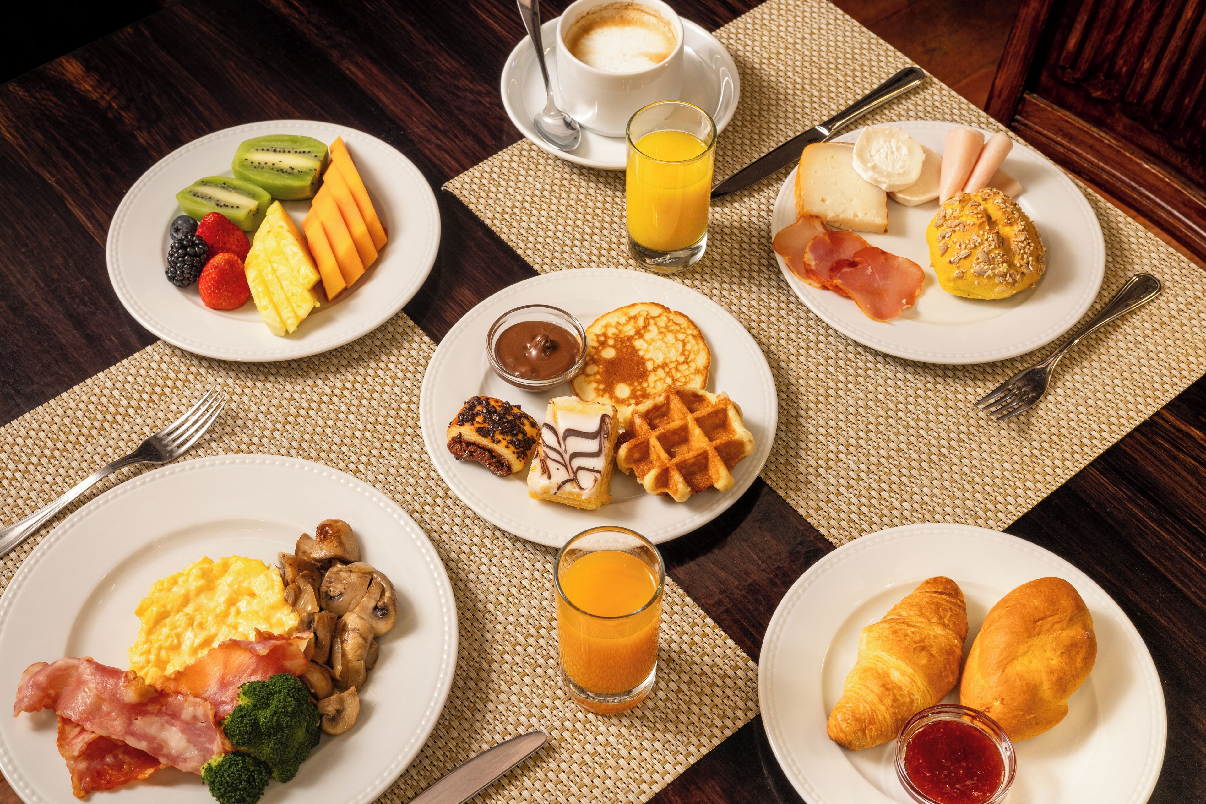 A breakfast spread with various dishes including eggs, bacon, toast, waffles, and fruit.