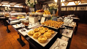 A buffet with various food items and a floral centerpiece. - SANA Rex Hotel (Lisbon)
