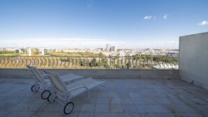 A rooftop terrace with two white lounge chairs and a view of a cityscape. - SANA Rex Hotel (Lisbon)
